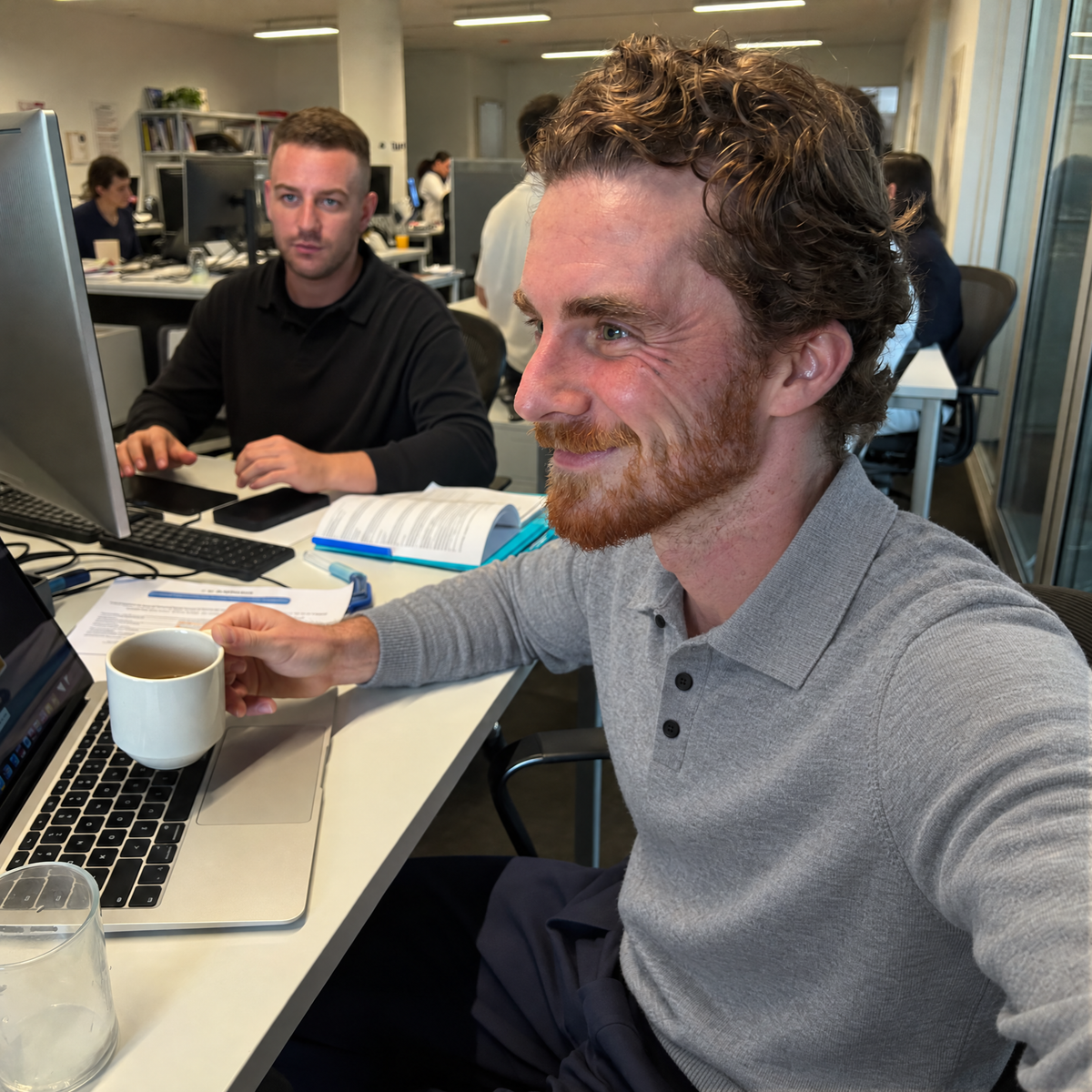 Man in a meeting at the office wearing the gray Bleamme Long Sleeve Knit Polo
