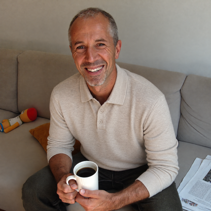 Man relaxing at home with coffee in the beige Bleamme Long Sleeve Knit Polo and jeans