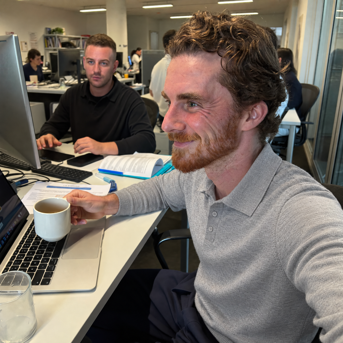 Man in a meeting at the office wearing the gray Bleamme Long Sleeve Knit Polo