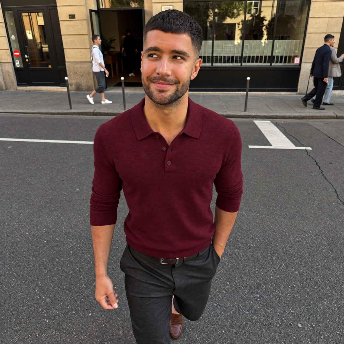 Man walking a city street in the red Bleamme Long Sleeve Knit Polo with charcoal trousers