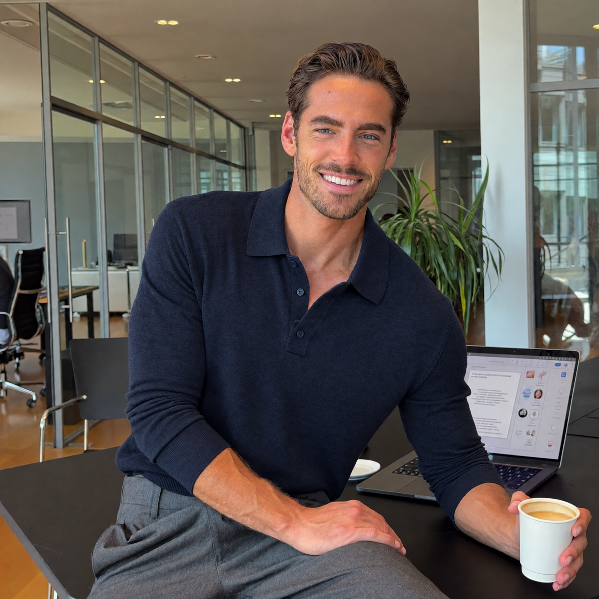 Man at the office wearing the dark blue Bleamme Long Sleeve Knit Polo with grey trousers