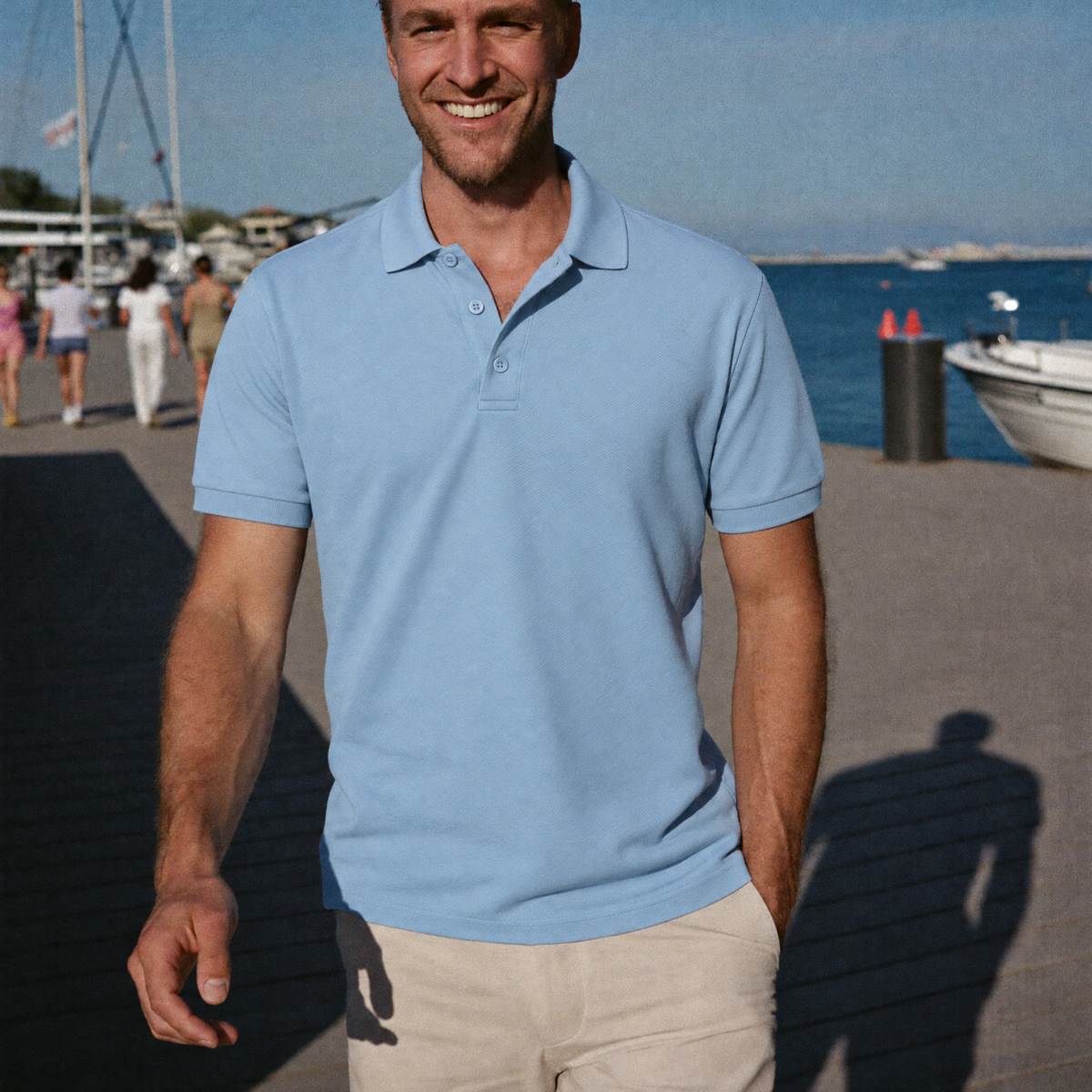Man walking on a sunny waterfront in the light blue Bleamme Short Sleeve Polo with stone chinos