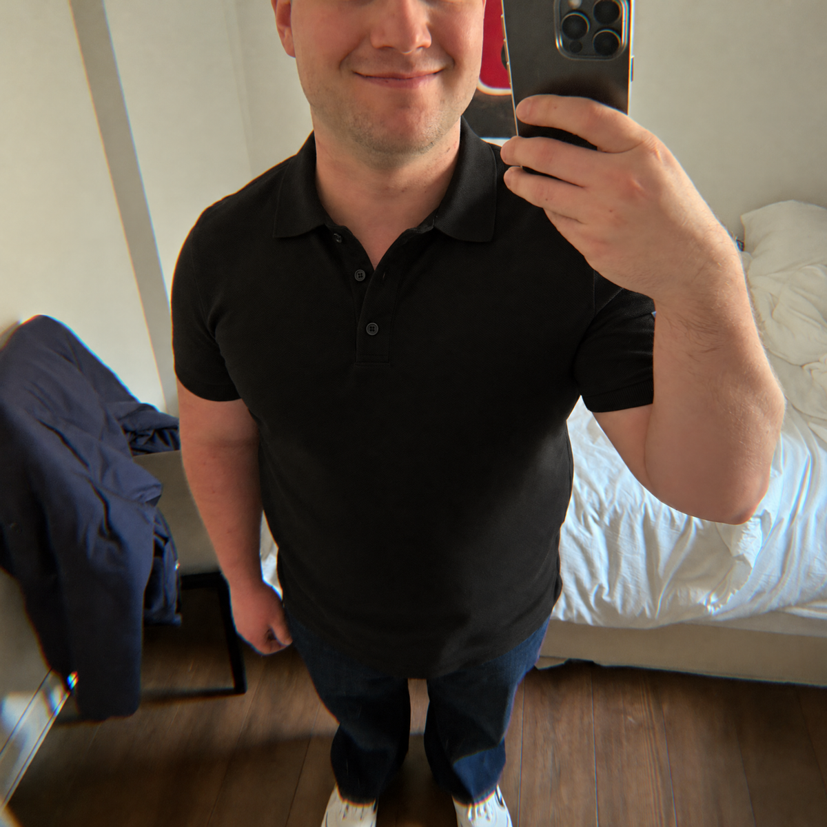 Mirror photo of the black Bleamme Short Sleeve Polo with dark jeans and white sneakers